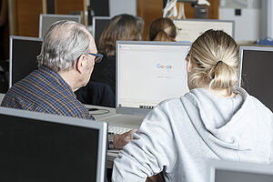 Dieses Foto wurde bei unserer PC-Schulung Jung hilft Alt aufgenommen. Ein Senior und eine Schülerin des Städtischen Von-Müller-Gymnasiums blicken auf einen eingeschalteten Computerbildschirm. Die PC-Schulung kann beginnen!